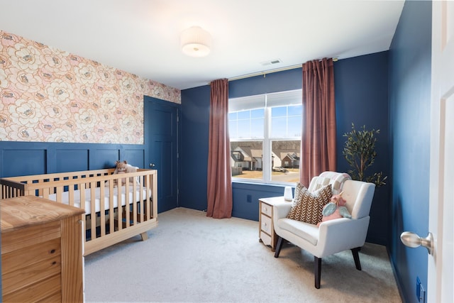 bedroom featuring a wainscoted wall, light colored carpet, visible vents, and wallpapered walls