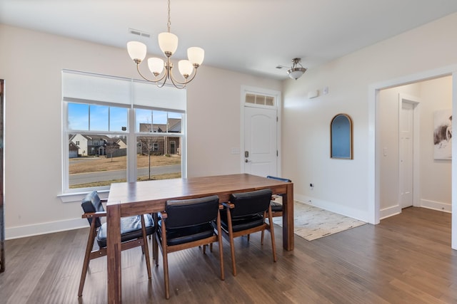 dining area featuring dark wood-type flooring, visible vents, baseboards, and a chandelier