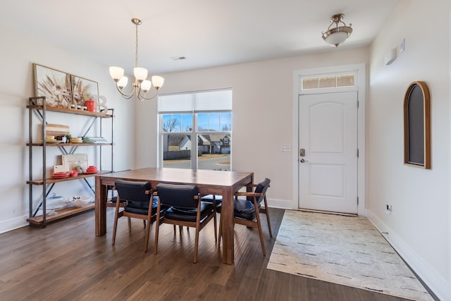 dining space with baseboards, a notable chandelier, and wood finished floors