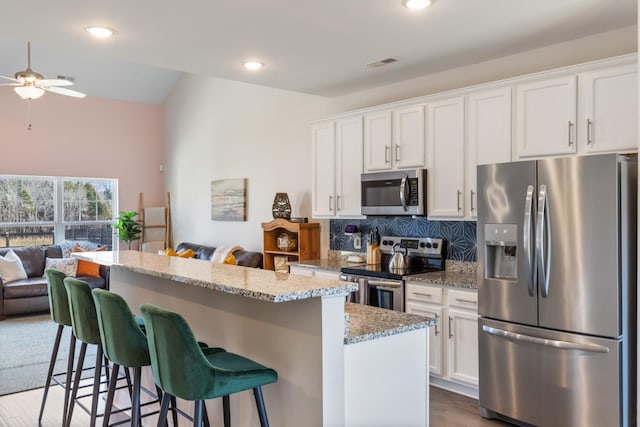 kitchen with visible vents, a kitchen island, ceiling fan, open floor plan, and appliances with stainless steel finishes