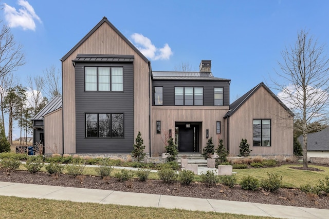 view of front of home featuring metal roof, a front yard, a chimney, and a standing seam roof