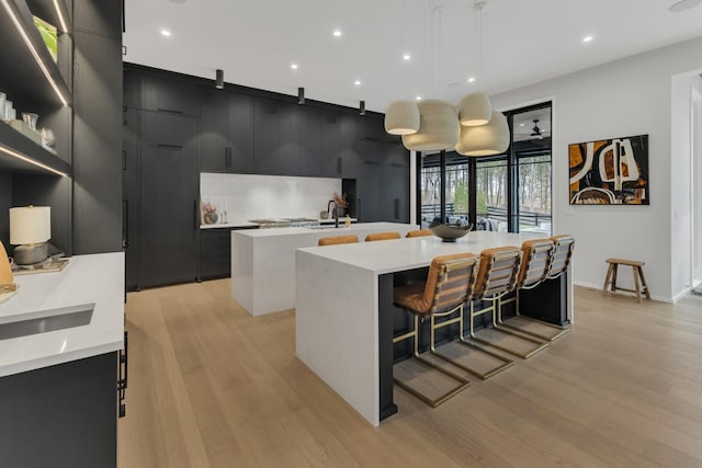 kitchen featuring light countertops, an island with sink, modern cabinets, and dark cabinets