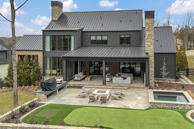 back of house featuring metal roof, a patio area, a chimney, and a standing seam roof