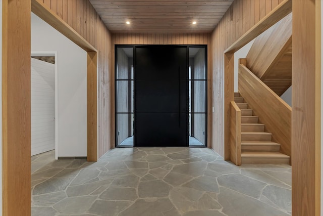 foyer featuring recessed lighting, stairway, wood walls, stone floors, and wood ceiling