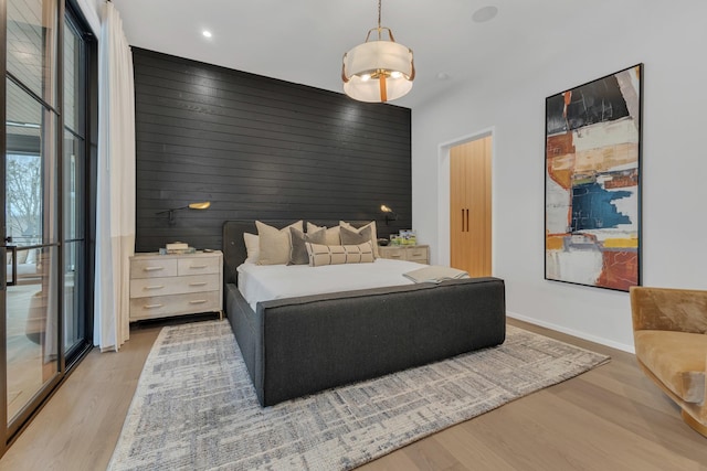 bedroom with wood walls, light wood-type flooring, and baseboards