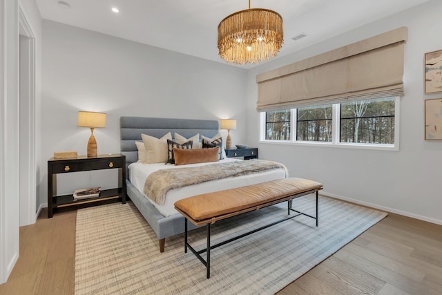 bedroom with visible vents, an inviting chandelier, baseboards, and wood finished floors