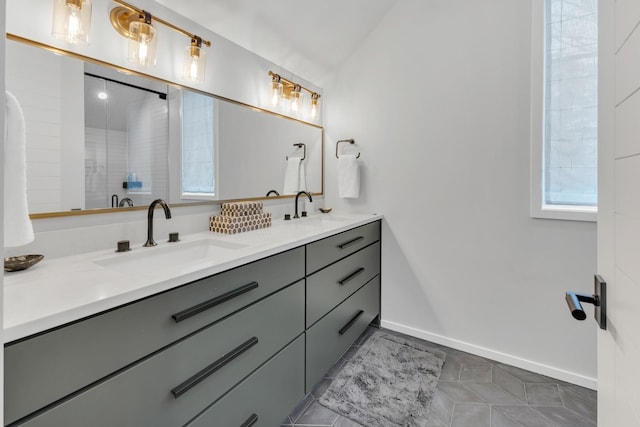 bathroom featuring double vanity, vaulted ceiling, baseboards, and a sink