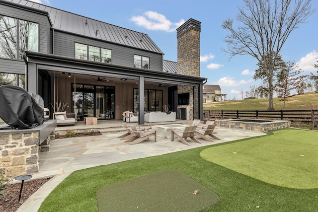 rear view of property with a patio, fence, a standing seam roof, an in ground hot tub, and metal roof