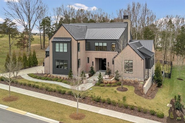 modern inspired farmhouse with a chimney, a front lawn, metal roof, and a standing seam roof