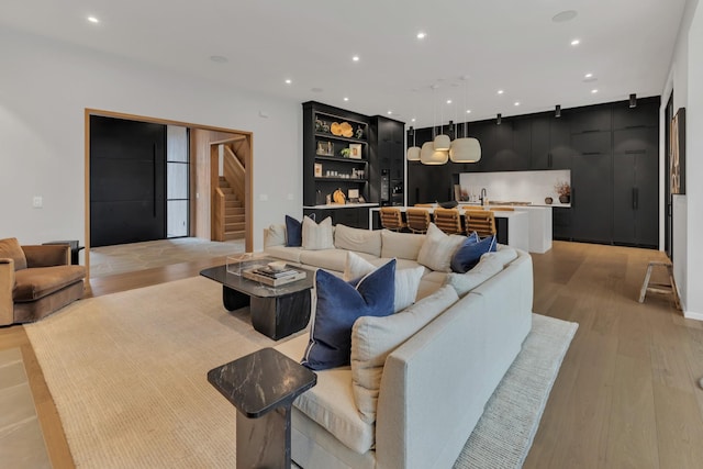 living area featuring recessed lighting, light wood-type flooring, and stairs