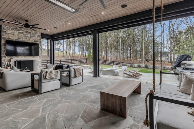 view of patio / terrace featuring fence, a ceiling fan, and an outdoor living space with a fireplace