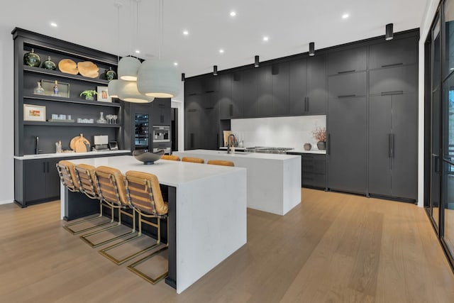 kitchen featuring a large island, modern cabinets, dark cabinetry, and light countertops