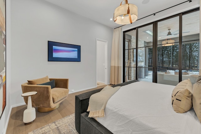 bedroom featuring baseboards, multiple windows, wood finished floors, and access to outside