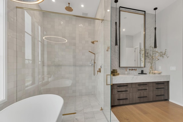 full bathroom with visible vents, wood finished floors, a shower stall, a freestanding bath, and vanity