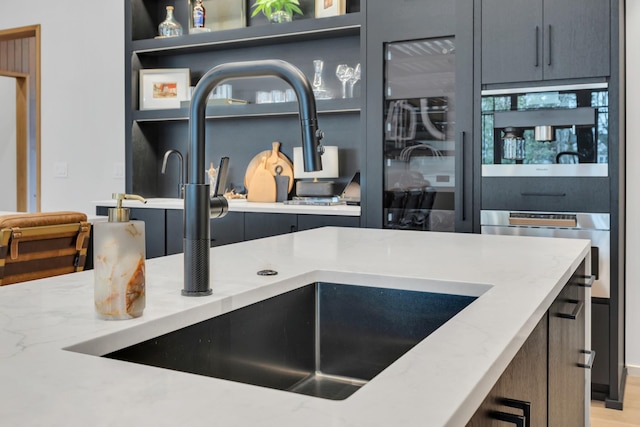 kitchen featuring light stone counters, wood finished floors, and a sink