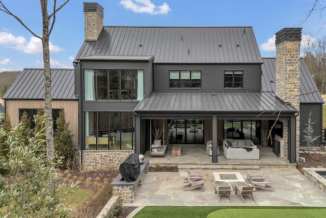 rear view of house with a standing seam roof, a patio, metal roof, and a chimney