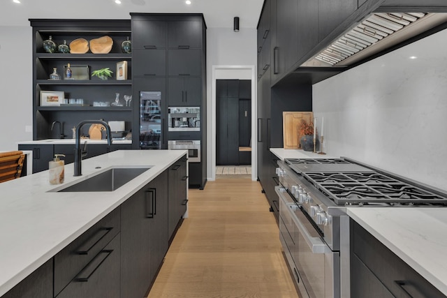 kitchen with double oven range, dark cabinetry, and a sink