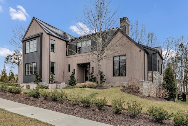 modern inspired farmhouse featuring a chimney, a front yard, and metal roof