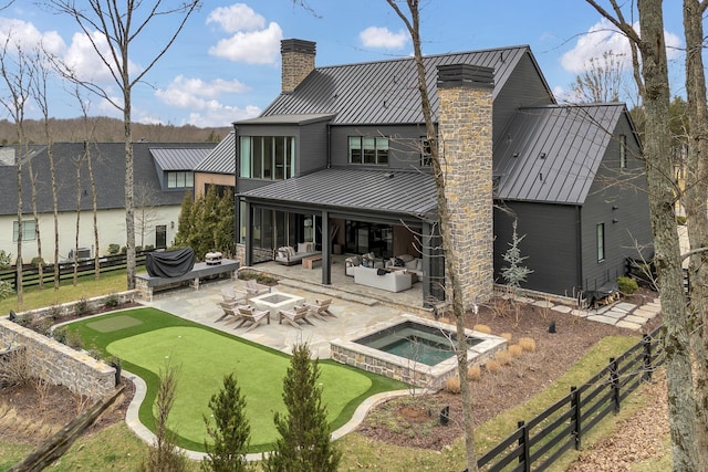 back of property featuring an outdoor hangout area, a chimney, metal roof, an outdoor hot tub, and a standing seam roof