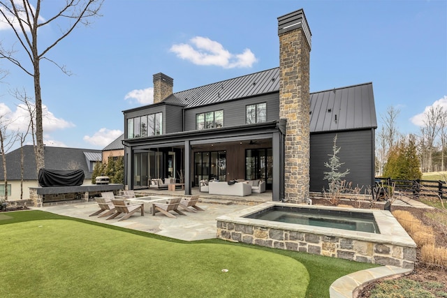 rear view of property featuring an outdoor hangout area, a chimney, metal roof, a patio area, and a standing seam roof