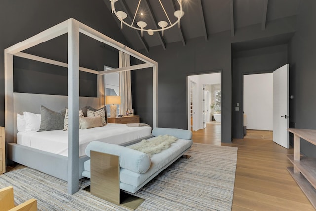 bedroom featuring beam ceiling, a notable chandelier, wood finished floors, and high vaulted ceiling