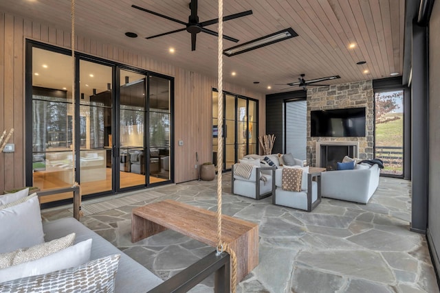 view of patio / terrace with an outdoor living space with a fireplace and a ceiling fan