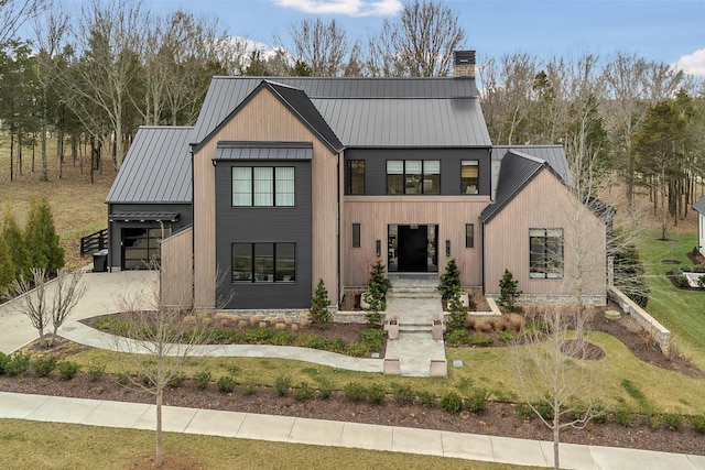 modern farmhouse style home featuring concrete driveway, a chimney, metal roof, a garage, and a standing seam roof