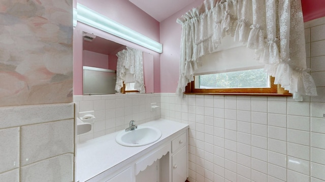 bathroom featuring a shower with shower door, a wainscoted wall, tile walls, and vanity