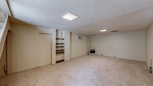 finished below grade area with an AC wall unit, heating unit, carpet floors, and a textured ceiling