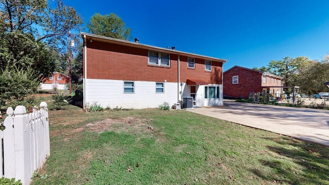 rear view of house with a lawn, fence, brick siding, central AC unit, and a patio area