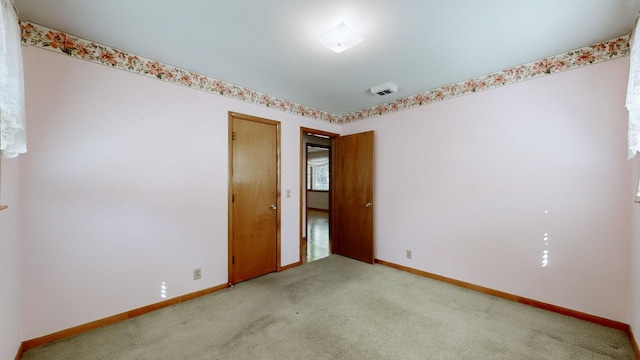 spare room featuring baseboards and light colored carpet