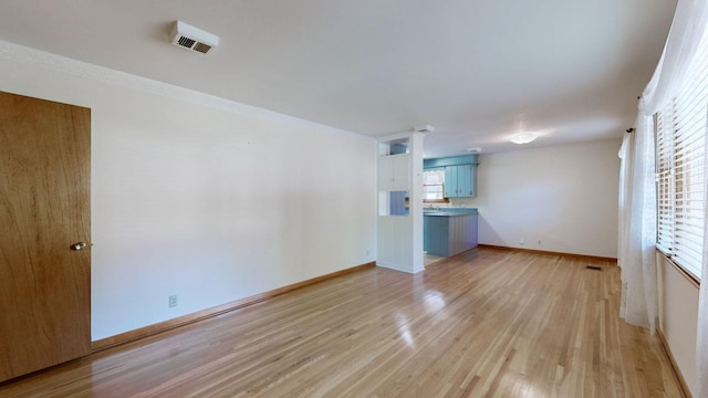 unfurnished living room with light wood-style flooring, visible vents, and baseboards