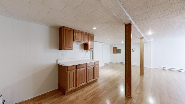 kitchen with a baseboard heating unit, light wood-style floors, and light countertops