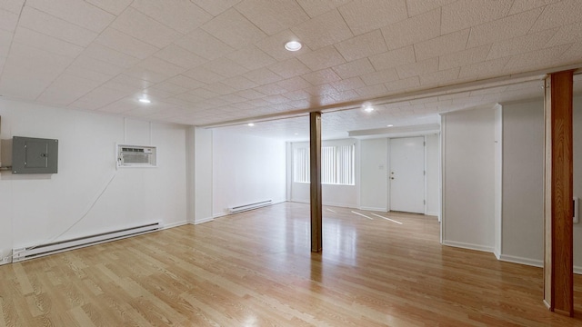 below grade area featuring an AC wall unit, electric panel, light wood-style floors, and a baseboard radiator