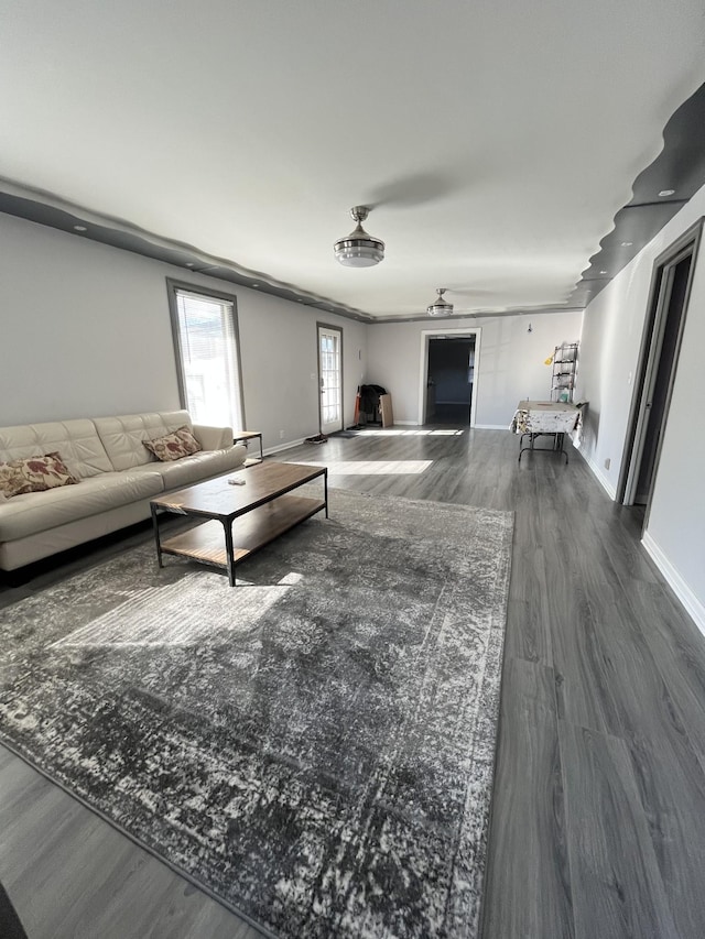 unfurnished living room featuring wood finished floors, baseboards, and ceiling fan