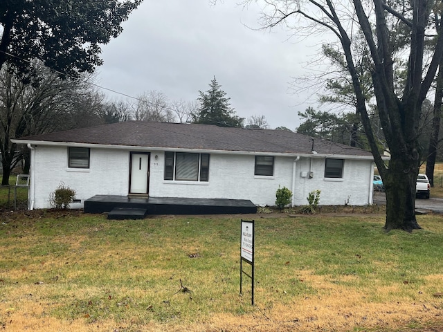 ranch-style home with a front yard, brick siding, and roof with shingles