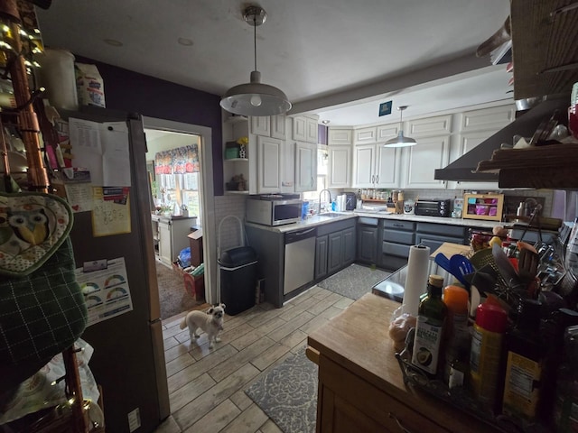 kitchen with wood finish floors, gray cabinets, a sink, appliances with stainless steel finishes, and hanging light fixtures