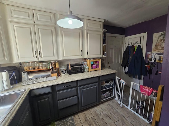 kitchen featuring a sink, light wood-type flooring, white cabinets, and decorative backsplash