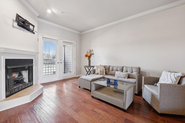 living area featuring hardwood / wood-style flooring, baseboards, a lit fireplace, and ornamental molding