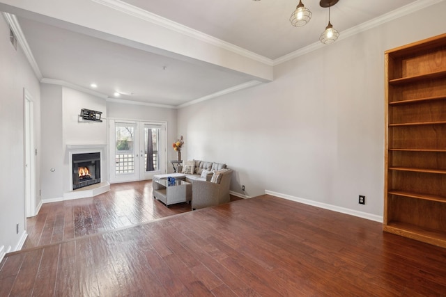 unfurnished living room with built in features, baseboards, ornamental molding, hardwood / wood-style flooring, and a glass covered fireplace