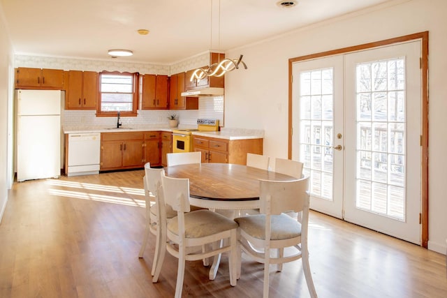 dining area featuring light wood-type flooring, french doors, and ornamental molding