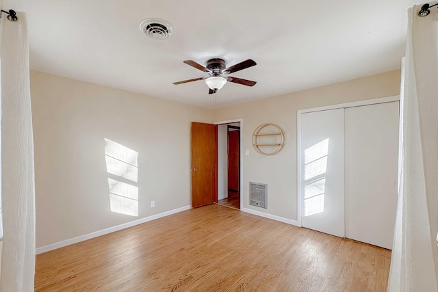 spare room with visible vents, heating unit, wood finished floors, baseboards, and ceiling fan