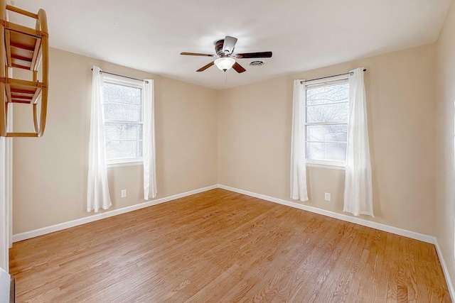 unfurnished room with plenty of natural light, light wood-style flooring, baseboards, and a ceiling fan