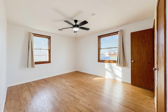 empty room with baseboards, ceiling fan, and light wood finished floors