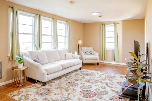 living area with a healthy amount of sunlight, baseboards, and wood finished floors