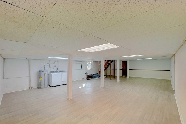 finished basement featuring washer and clothes dryer, a drop ceiling, water heater, light wood finished floors, and stairs