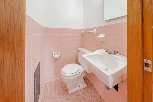 half bath with visible vents, a wainscoted wall, toilet, tile walls, and tile patterned flooring