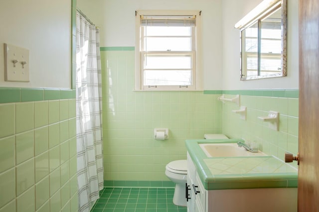 full bath featuring a wainscoted wall, toilet, tile walls, tile patterned flooring, and vanity