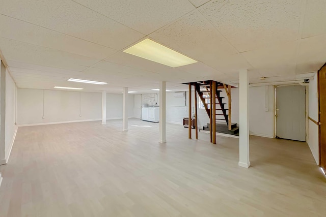 finished basement featuring washer and clothes dryer, stairway, light wood-style flooring, and baseboards