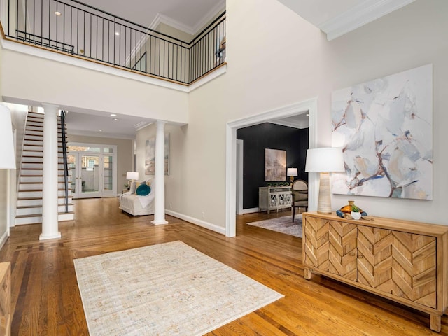 foyer featuring baseboards, stairway, ornamental molding, decorative columns, and wood finished floors